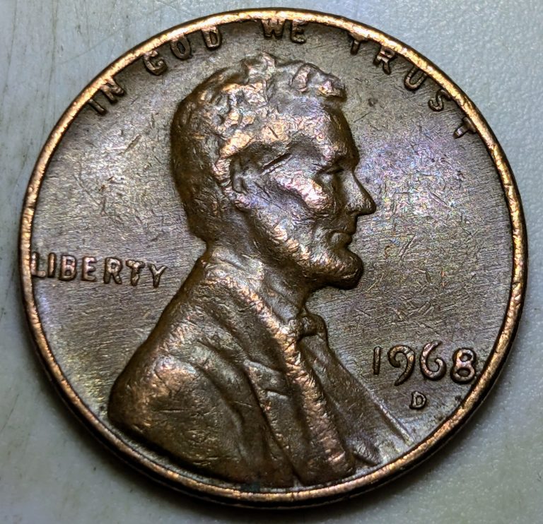 Another 1968-D cent showing the same pushed-in rim distortion. The flattened motto and spread lettering are caused by a clamp or vise after minting.