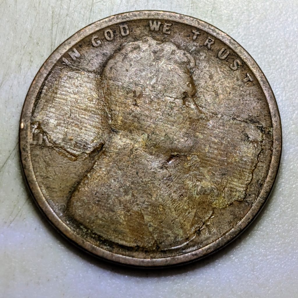 A heavily damaged Wheat cent with severe environmental corrosion across the obverse, showing deep surface loss and discoloration.