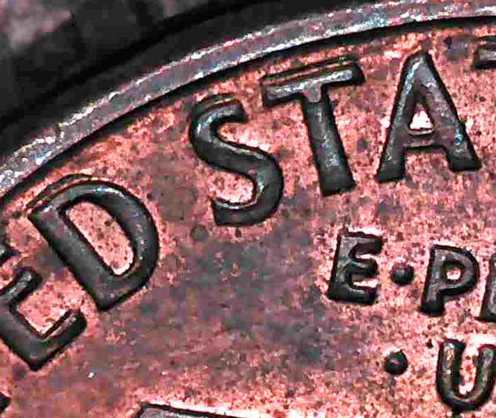 Close-up of a 1989 Lincoln cent showing die deterioration doubling on the letters of UNITED STATES, with flat, shelf-like distortion typical of machine doubling.
