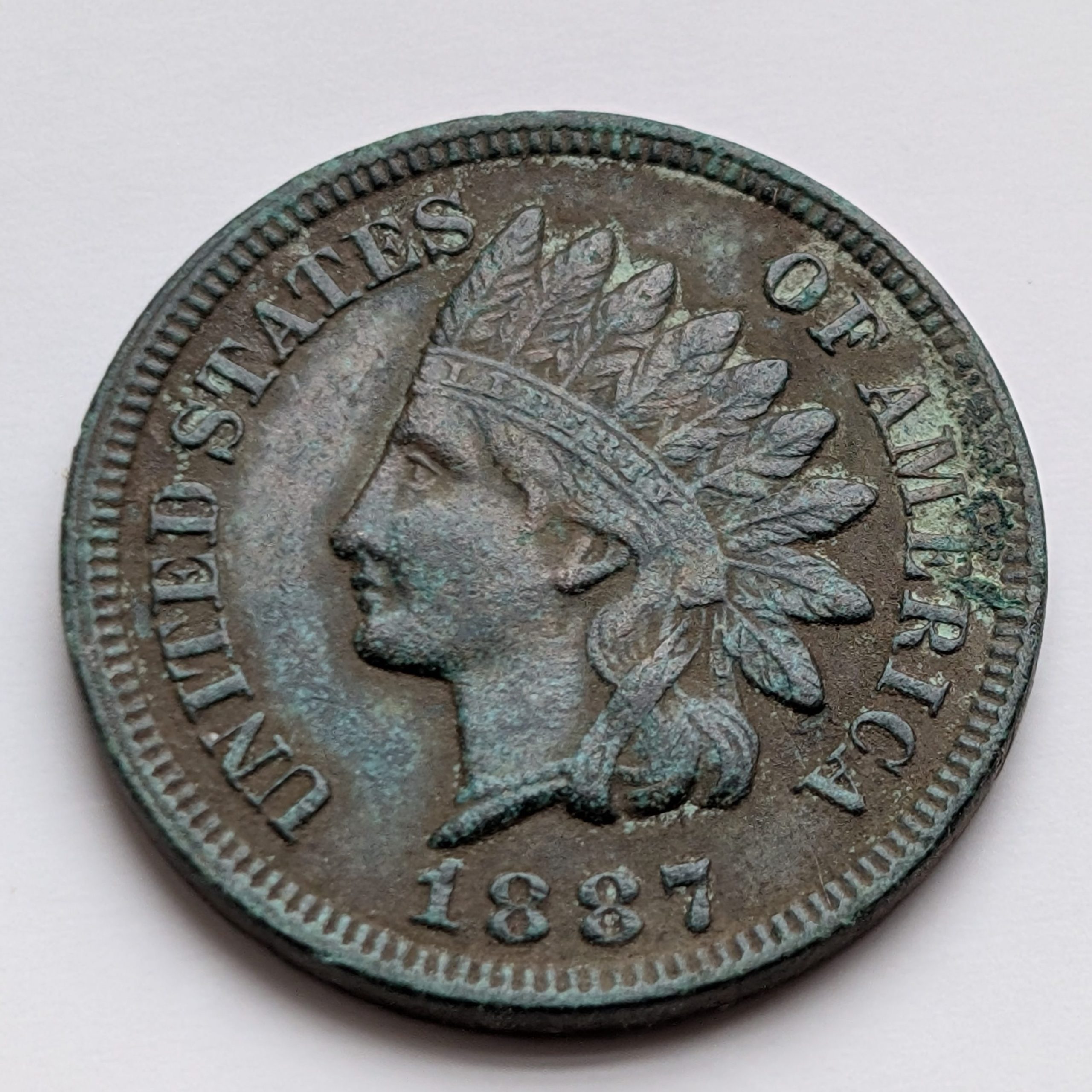 1887 Indian Head cent with advanced verdigris. A perfect example of how copper reacts to decades of moisture and air exposure.