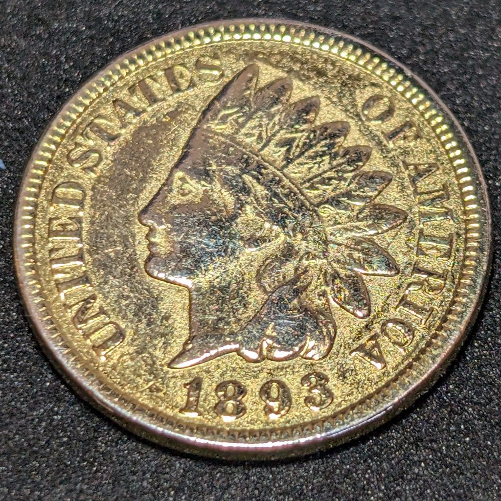 1893 Indian Head cent with unnaturally bright, glossy surfaces and visible scratch lines from polishing or whizzing.