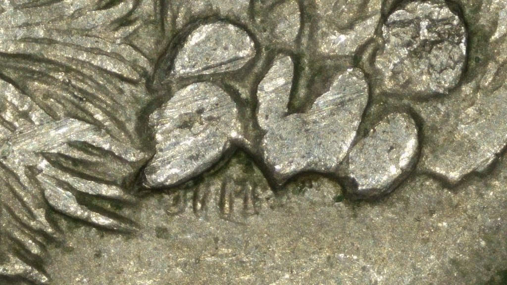 Close-up of a die chip on the reverse of a 2008 Arizona state quarter showing raised metal in the cactus design.