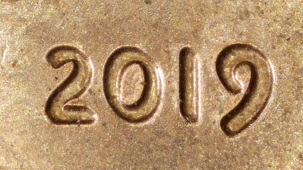 Close-up of the 2019 Lincoln cent date showing doubled die characteristics with a lopsided 0 and uneven inner wall thickness.